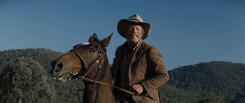 Movie still from “The Man from Snowy River” (1982), directed by George Miller – A man in a cowboy hat is riding a horse; Medium shot, Low angle