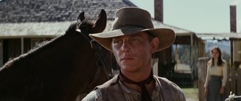 Movie still from “The Man from Snowy River” (1982), directed by George Miller – A man wearing a cowboy hat standing next to a horse; Close Up shot, Low angle