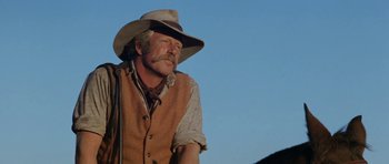 Movie still from “The Man from Snowy River” (1982), directed by George Miller – An older man wearing a cowboy hat and vest; Medium shot, Low angle