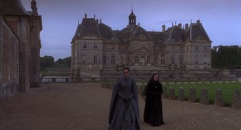 Movie still from “The Man in the Iron Mask” (1998), directed by Randall Wallace – A man and a woman dressed in medieval garb in front of a castle; Extreme Wide shot, Low angle