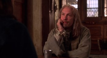 Movie still from “The Man in the Iron Mask” (1998), directed by Randall Wallace – A man sitting at a table with his hand under his chin; Close Up shot, Over the shoulder angle