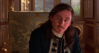 Movie still from “The Man in the Iron Mask” (1998), directed by Randall Wallace – A man with long hair sitting in a chair; Close Up shot, Over the shoulder angle