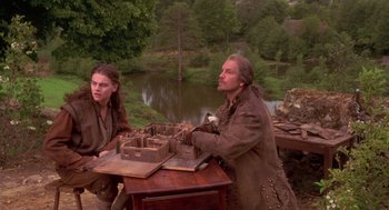 Movie still from “The Man in the Iron Mask” (1998), directed by Randall Wallace – A man and a woman sitting at a wooden table; Medium shot, Over the shoulder angle