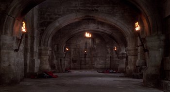 Movie still from “The Man in the Iron Mask” (1998), directed by Randall Wallace – An archway in an old stone building with fire; Extreme Wide shot, High angle