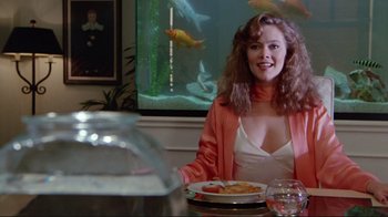 Movie still from “The Man with Two Brains” (1983), directed by Carl Reiner – A woman sitting at a table with a plate in front of her; Medium shot, Over the shoulder angle