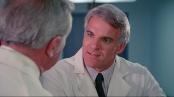 Movie still from “The Man with Two Brains” (1983), directed by Carl Reiner – A man wearing a lab coat talking to another man in front of a mirror; Close Up shot, Over the shoulder angle