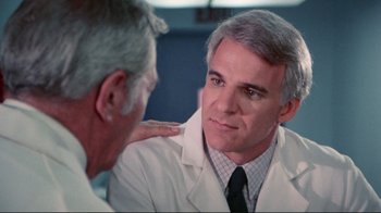 Movie still from “The Man with Two Brains” (1983), directed by Carl Reiner – A man wearing a lab coat talking to another man in a white lab coat; Close Up shot, Over the shoulder angle