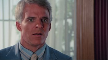 Movie still from “The Man with Two Brains” (1983), directed by Carl Reiner – A man in a suit and tie looking surprised; Close Up shot, Over the shoulder angle