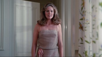 Movie still from “The Man with Two Brains” (1983), directed by Carl Reiner – A woman in a dress standing next to a door; Medium shot, Low angle