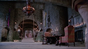 Movie still from “The Man with Two Brains” (1983), directed by Carl Reiner – A room filled with furniture and a stone wall; Extreme Wide shot, High angle