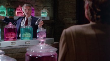 Movie still from “The Man with Two Brains” (1983), directed by Carl Reiner – A man in a suit and tie holding a jar; Medium shot, Over the shoulder angle
