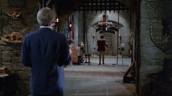 Movie still from “The Man with Two Brains” (1983), directed by Carl Reiner – A man standing in front of a woman in a room; Wide shot, Over the shoulder angle