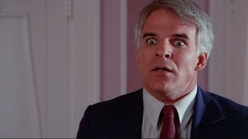 Movie still from “The Man with Two Brains” (1983), directed by Carl Reiner – An older man in a suit and tie looking surprised; Close Up shot, Over the shoulder angle