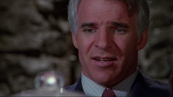 Movie still from “The Man with Two Brains” (1983), directed by Carl Reiner – A man in a suit and a red tie looking to his left; Close Up shot, Over the shoulder angle