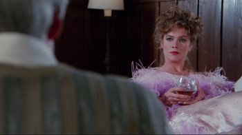 Movie still from “The Man with Two Brains” (1983), directed by Carl Reiner – A woman is holding a wine glass in front of a mirror; Medium shot, Over the shoulder angle