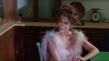Movie still from “The Man with Two Brains” (1983), directed by Carl Reiner – A woman sitting in a chair wearing a pink and white dress; Close Up shot, Over the shoulder angle