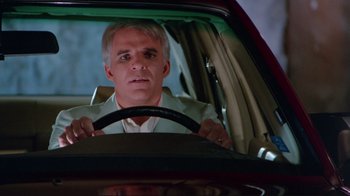 Movie still from “The Man with Two Brains” (1983), directed by Carl Reiner – A man driving a car at night in the dark; Close Up shot, Over the shoulder angle