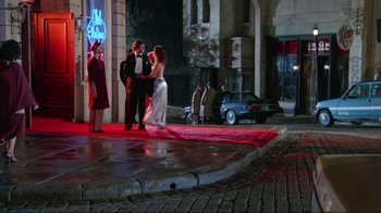 Movie still from “The Man with Two Brains” (1983), directed by Carl Reiner – A group of people standing on a red carpet on a sidewalk; Wide shot, Over the shoulder angle