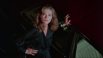 Movie still from “The Man with Two Brains” (1983), directed by Carl Reiner – A woman standing next to a car in a dark room; Medium shot, Low angle