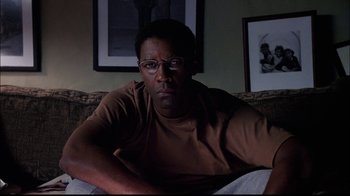 Movie still from “The Manchurian Candidate” (2004), directed by Jonathan Demme – A man sitting on top of a couch in a living room; Close Up shot, Over the shoulder angle