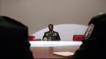Movie still from “The Manchurian Candidate” (2004), directed by Jonathan Demme – A man sitting at a table in front of papers; Medium shot, Over the shoulder angle