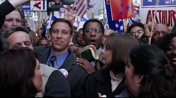 Movie still from “The Manchurian Candidate” (2004), directed by Jonathan Demme – A group of people standing around each other holding a book; Medium shot, Over the shoulder angle