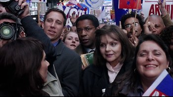 Movie still from “The Manchurian Candidate” (2004), directed by Jonathan Demme – A group of people standing around each other holding signs; Close Up shot, Over the shoulder angle
