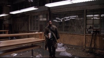 Movie still from “The Manchurian Candidate” (2004), directed by Jonathan Demme – A man standing in an abandoned building holding a book; Wide shot, Low angle