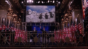 Movie still from “The Manchurian Candidate” (2004), directed by Jonathan Demme – Three men standing in front of a large screen; Extreme Wide shot, Low angle