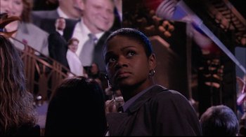 Movie still from “The Manchurian Candidate” (2004), directed by Jonathan Demme – A woman standing in front of a picture of a man; Medium shot, Over the shoulder angle