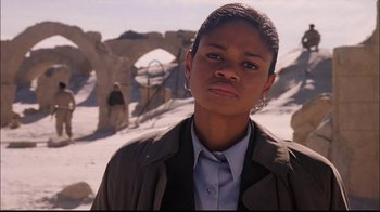 Movie still from “The Manchurian Candidate” (2004), directed by Jonathan Demme – A woman in a brown jacket standing in front of a stone structure; Close Up shot, Low angle