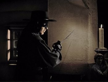 Movie still from “The Mark of Zorro” (1940), directed by Rouben Mamoulian – A man in a black hat and black gloves holding a knife in his hand; Medium shot, Over the shoulder angle