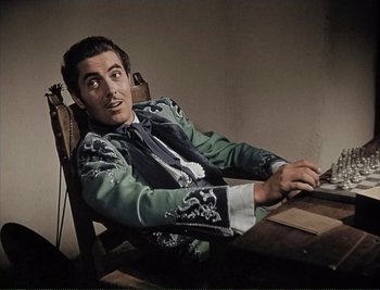 Movie still from “The Mark of Zorro” (1940), directed by Rouben Mamoulian – A man sitting at a table wearing a suit and tie; Medium shot, High angle