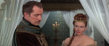 Movie still from “The Masque of the Red Death” (1964), directed by Roger Corman – A man and a woman standing next to each other in front of candles; Medium shot, Over the shoulder angle