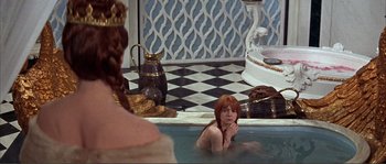 Movie still from “The Masque of the Red Death” (1964), directed by Roger Corman – A woman sitting in a bath tub next to a man; Medium shot, High angle