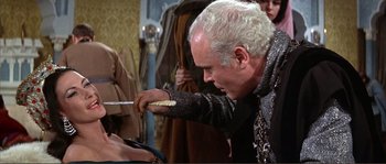 Movie still from “The Masque of the Red Death” (1964), directed by Roger Corman – An older man holding a knife in his hand; Close Up shot, Over the shoulder angle