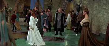 Movie still from “The Masque of the Red Death” (1964), directed by Roger Corman – A group of people standing around in a room; Wide shot, Over the shoulder angle