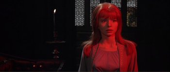 Movie still from “The Masque of the Red Death” (1964), directed by Roger Corman – A woman with red hair standing next to a lit candle; Medium shot, Over the shoulder angle