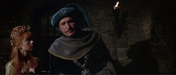Movie still from “The Masque of the Red Death” (1964), directed by Roger Corman – A man wearing a blue hat and a black robe; Medium shot, Over the shoulder angle