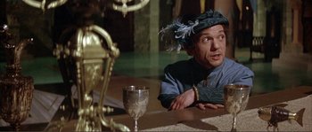 Movie still from “The Masque of the Red Death” (1964), directed by Roger Corman – A man wearing a hat sitting at a dinner table; Medium shot, High angle
