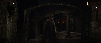 Movie still from “The Masque of the Red Death” (1964), directed by Roger Corman – A man in a hooded cloak stands in a dark room; Wide shot, High angle