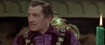 Movie still from “The Masque of the Red Death” (1964), directed by Roger Corman – A person sitting on a chair wearing a suit; Close Up shot, Over the shoulder angle