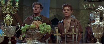 Movie still from “The Masque of the Red Death” (1964), directed by Roger Corman – Two men in medieval garb standing in front of a table; Medium shot, Over the shoulder angle