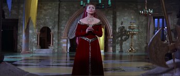 Movie still from “The Masque of the Red Death” (1964), directed by Roger Corman – A woman in a red dress standing in front of an archway; Wide shot, Low angle