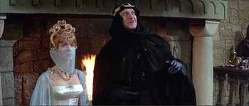 Movie still from “The Masque of the Red Death” (1964), directed by Roger Corman – A man in a black robe and a woman in a white dress; Medium shot, Low angle