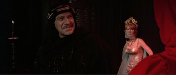 Movie still from “The Masque of the Red Death” (1964), directed by Roger Corman – A man in a black robe and a woman in a white dress; Close Up shot, Over the shoulder angle