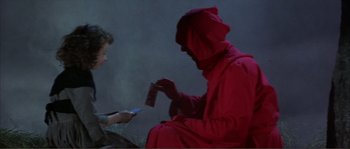 Movie still from “The Masque of the Red Death” (1964), directed by Roger Corman – A person in a red costume is holding a cell phone; Medium shot, High angle