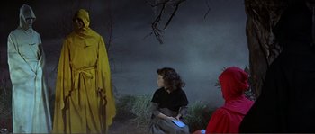 Movie still from “The Masque of the Red Death” (1964), directed by Roger Corman – A woman in a black shirt is holding a book in her hand; Medium shot, Low angle