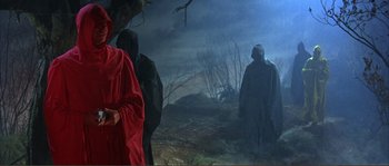 Movie still from “The Masque of the Red Death” (1964), directed by Roger Corman – A group of people standing in the dark; Medium shot, Low angle