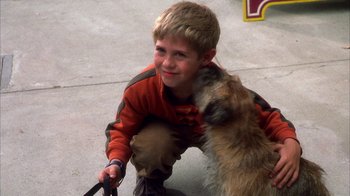 Movie still from “The Master of Disguise” (2002), directed by Perry Andelin Blake – A boy and a dog are smiling for the camera; Close Up shot, Over the shoulder angle